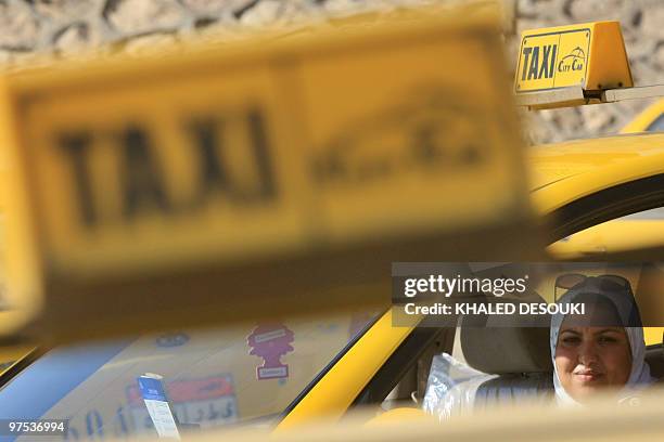 Egyptian taxi driver Ines Hassan waits for customers in her car in Cairo on March 6, 2010. The 36-year-old taxi driver is one of several women...