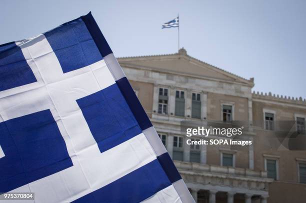 Greek flag seen front of the Greek Parliament at the demonstration. People demonstrated in Syntagma square, Athens, in protest at the Greek...