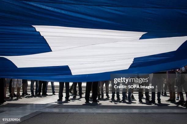 People seen holding a large Greek flag and shouting slogans at the demonstration. People demonstrated in Syntagma square, Athens, in protest at the...