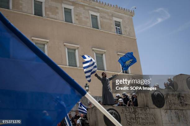 Priest seen holding Greek and Macedonia flags front of the Greek Parliament at the demonstration. People demonstrated in Syntagma square, Athens, in...