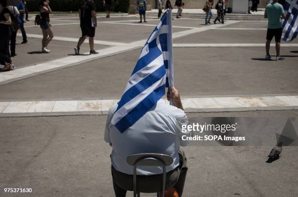 Demonstrator seen sitting and holding a Greek flag at the demonstration. People demonstrated in Syntagma square, Athens, in protest at the Greek...
