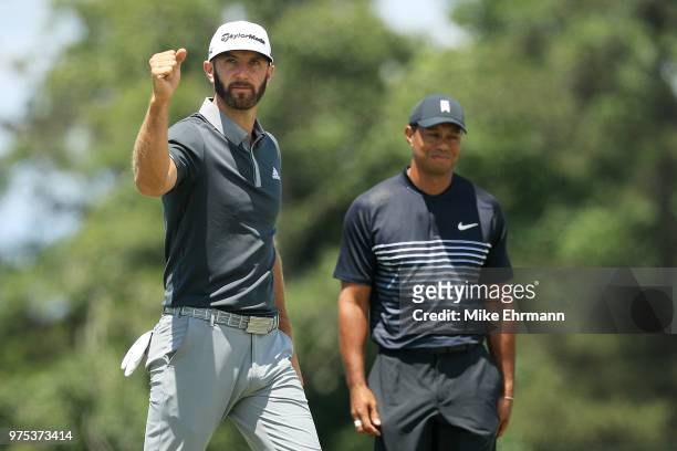 Dustin Johnson of the United States celebrates making a birdie on the seventh hole as Tiger Woods of the United States looks on during the second...