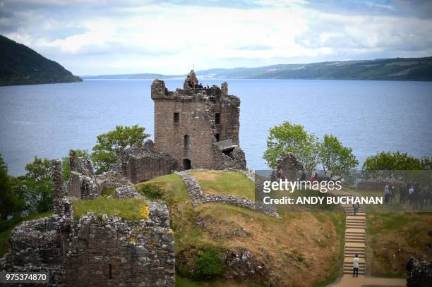 Tourists take in Urquhart Castle on the banks of Loch Ness in the Scottish Highlands, Scotland on June 10, 2018.