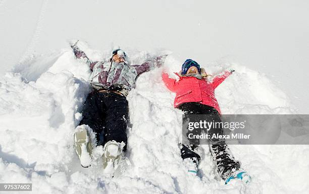 two young women making snow angels. - alta stock-fotos und bilder