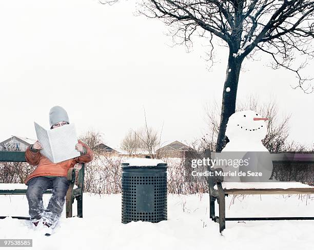 boy reading on bench by snowman - muriel stock pictures, royalty-free photos & images