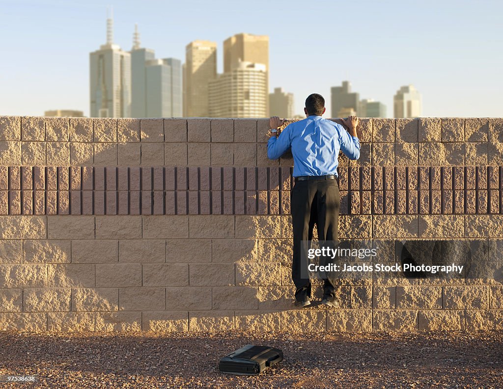 Businessman Looking over Wall at City