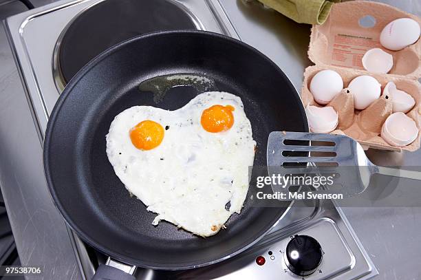 heart shaped fried eggs in a pan, sunny side up  - setzei stock-fotos und bilder