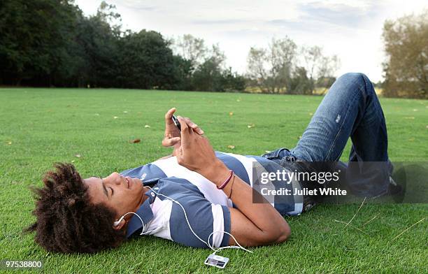 teenage boy lying on the grass using mobile phone  - boy ipod stock pictures, royalty-free photos & images