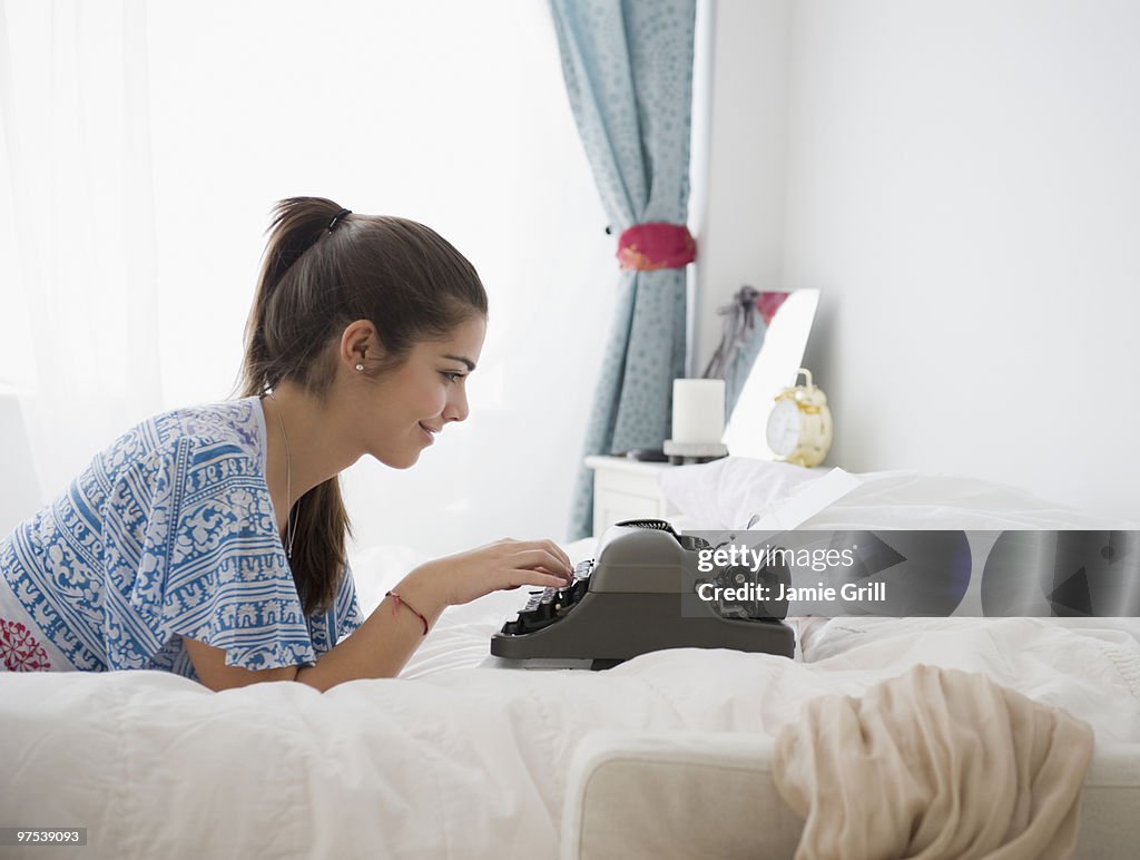 Teenage girl typing on antique typewriter, smiling