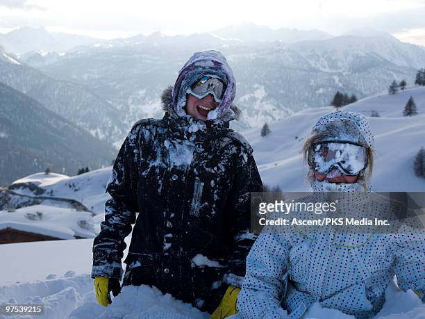 snow covered kids smile towards camera,mtns behind - sestriere stock-fotos und bilder