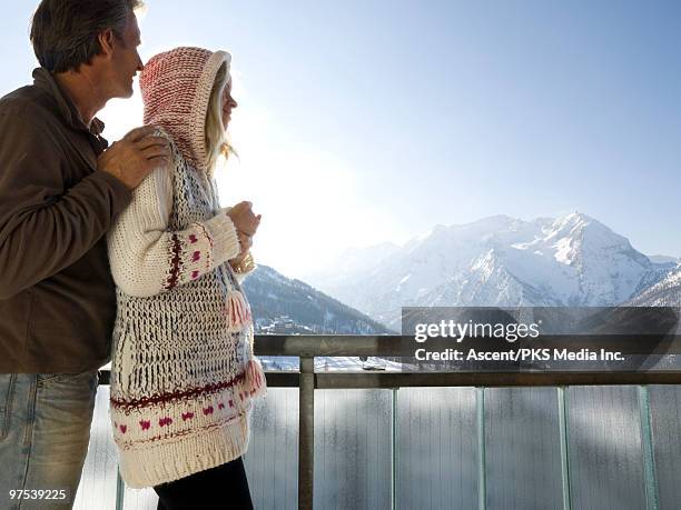 couple look across snowy mtn landscape from deck - sestriere stock-fotos und bilder