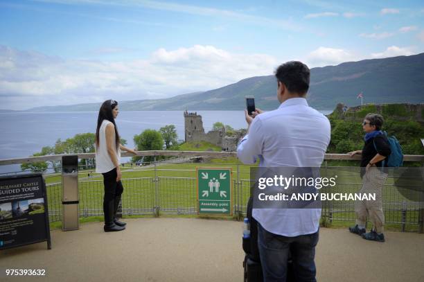 Tourists take in Urquhart Castle on the banks of Loch Ness in the Scottish Highlands, Scotland on June 10, 2018.