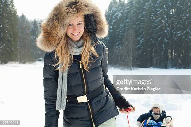 woman pulling sledge with babygirl - kathrin ziegler stockfoto's en -beelden