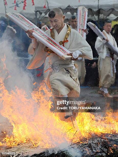 Holding a talisman, a Buddhist monk walks barefoot over fire as he takes part in the traditional "hi-watari", or fire-walking ritual, which heralds...