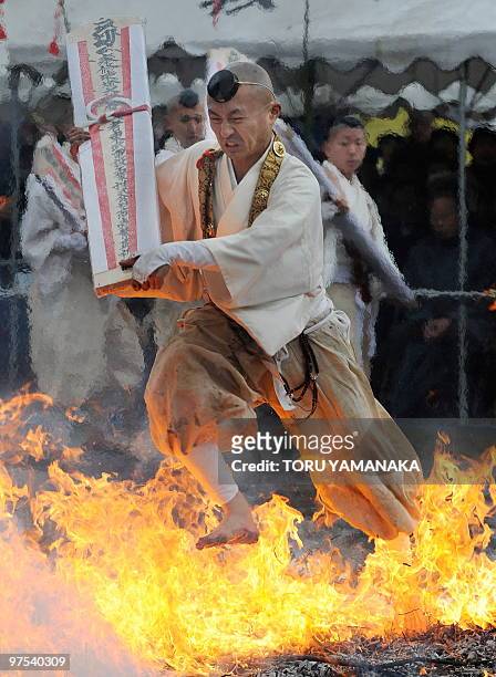 Holding a talisman, a Buddhist monk runs barefoot over fire as he takes part in the traditional "hi-watari", or fire-walking ritual, which heralds...
