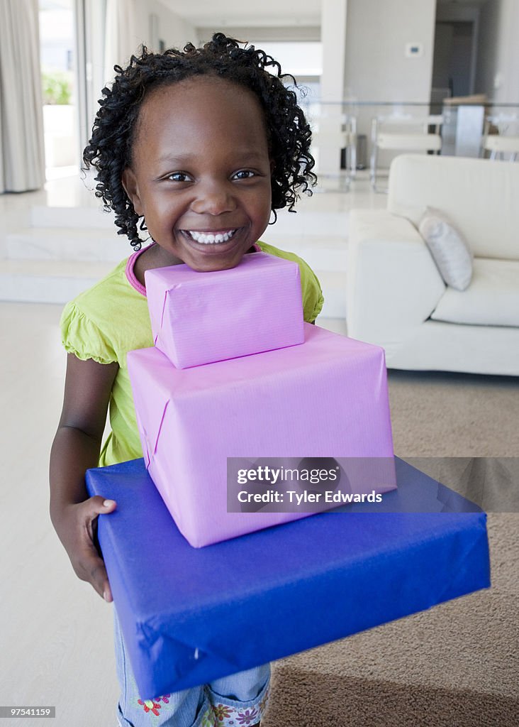 Girl smiling holding big pile of presents