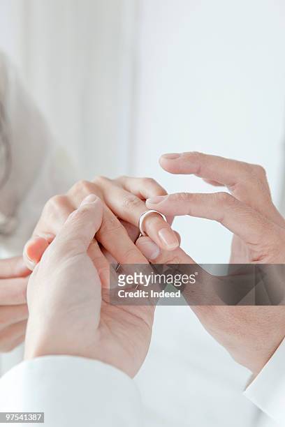 man putting wedding ring on woman's finger - engagement bildbanksfoton och bilder