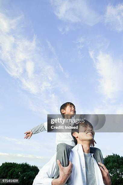 father carrying son on shoulders, low angle view - carrying a person on shoulders stock pictures, royalty-free photos & images