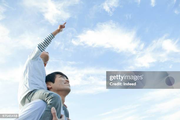 father carrying son(4-5) on shoulders, looking up - person auf den schultern tragen stock-fotos und bilder