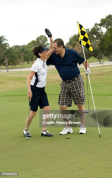 mature latin couple on golf course having fun. - boca raton stock pictures, royalty-free photos & images