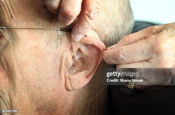 a hearing aide is inserted - shana novak stockfoto's en -beelden