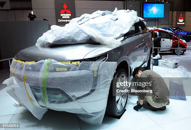 An employee inspects a Mitsubishi PX-MiEV concept automobile prior to the official opening of the Geneva International Motor Show in Geneva,...