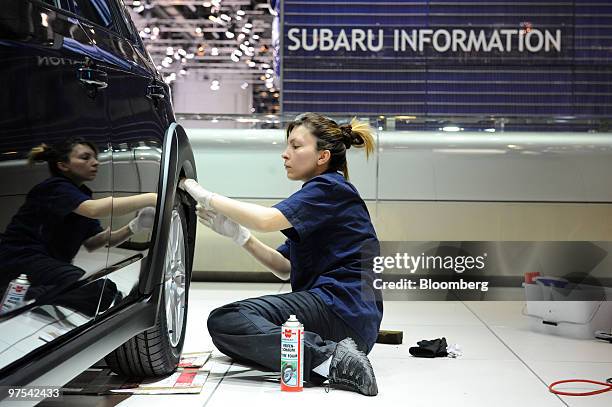 An employee cleans a Subaru automobile prior to the official opening of the Geneva International Motor Show in Geneva, Switzerland, on Monday, March...