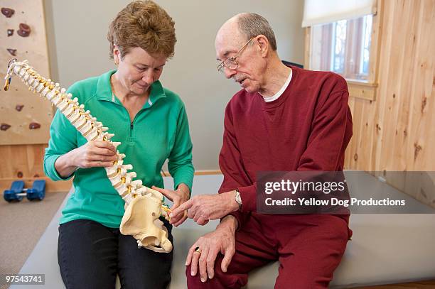 physical therapist showing spine to client - physical position - fotografias e filmes do acervo