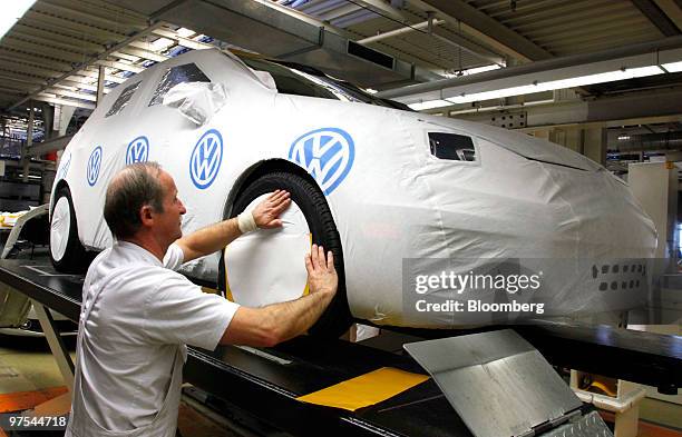 Worker places the protective covering on a finished VW automobile at the Volkswagen AG factory in Wolfsburg, Germany, on Monday, March 8, 2010....