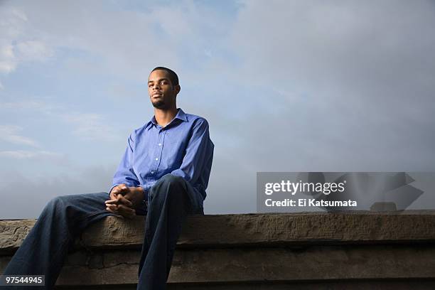 portrait of a young man sitting on a ledge - ei 個照片及圖片檔