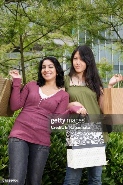 portrait of two young women holding shopping bags - ei 個照片及圖片檔