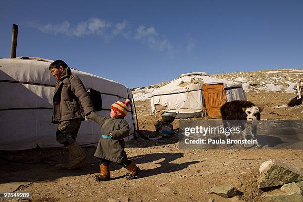 Mongolian herder and his child walk into their Ger, a traditional nomadic home, in the frozen landscape on March 8, 2010 in Bayantsogt, Tuv province,...