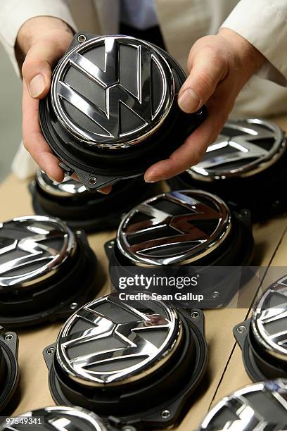 In this photo illustration a worker arranges VW rear hood ornaments for Volkswagen Golf cars at the assembly line at the VW factory on March 8, 2010...