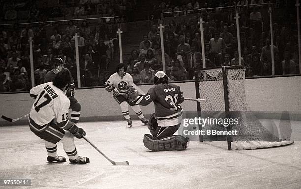 Goalie Gary Inness of the Pittsburgh Penguins looks to make the save as Jean-Paul Parise and teammate Jude Drouin of the New York Islanders look to...