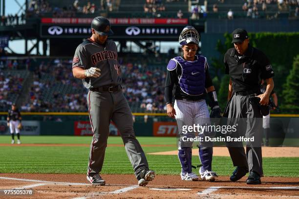 Paul Goldschmidt of the Arizona Diamondbacks touches home plate in front of Tony Wolters of the Colorado Rockies after hitting a first inning homerun...