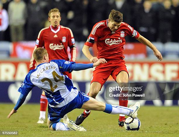 Steven Gerrard of Liverpool competes with James McCarthy of Wigan during the Barclays Premier League match between Wigan Athletic and Liverpool at...