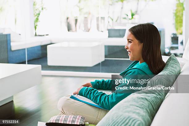 girl with book sitting on sofa - chesterfield sofa stock pictures, royalty-free photos & images