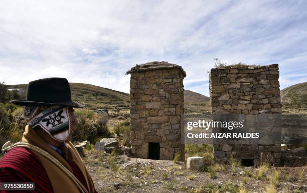 Man looks at two restored pre-Inca funerary towers known as chullpas, erected at the Qala Uta archaeological site near Quehuaya, on the slopes of the...