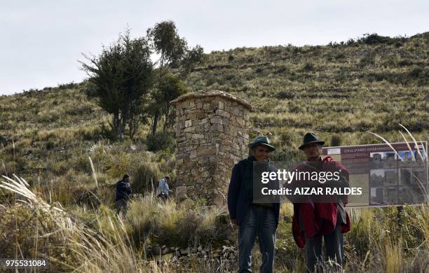 Men stand near a restored pre-Inca funerary tower known as chullpa, at the Qala Uta archaeological site near Quehuaya, on the slopes of the hills...