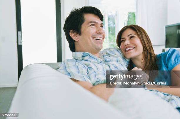 couple laughing on sofa - chesterfield sofa stock pictures, royalty-free photos & images