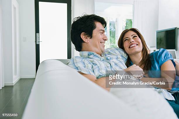 couple laughing on sofa - chesterfield sofa stock pictures, royalty-free photos & images