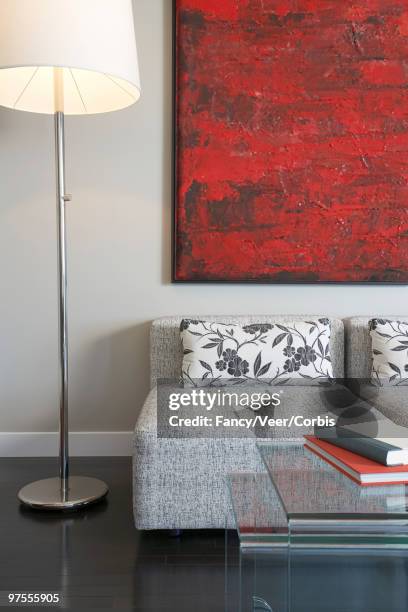 living room - a woman modelling a trouser suit blends in with a matching background of floral print cushions stockfoto's en -beelden