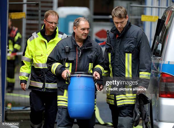 June 2018, Germany, Cologne: A firefighter carrying a barrel out of the residential complex Osloerstr. 3 in Cologne-Chorweiler. The police is...