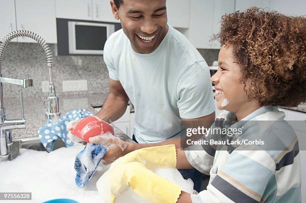 father and son washing dishes - kids with cleaning rubber gloves stock-fotos und bilder