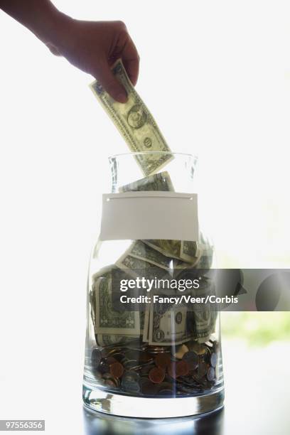 hand putting money in a jar - positioned stock pictures, royalty-free photos & images