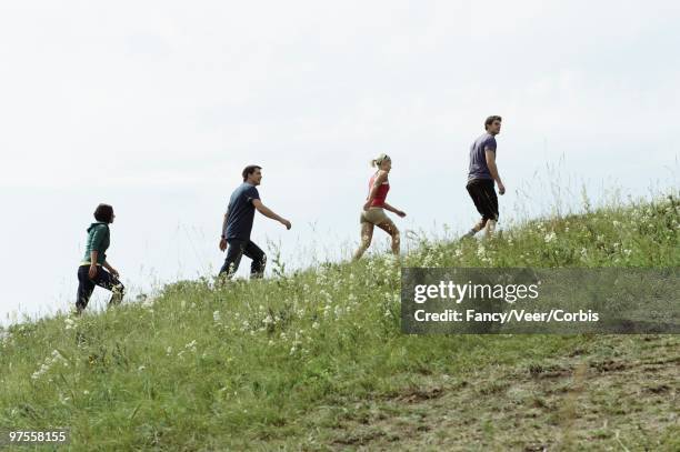 friends climbing a hill - steil haar stock-fotos und bilder