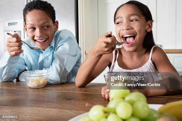 brother and sister eating breakfast - girl sitting on boys face fotografías e imágenes de stock