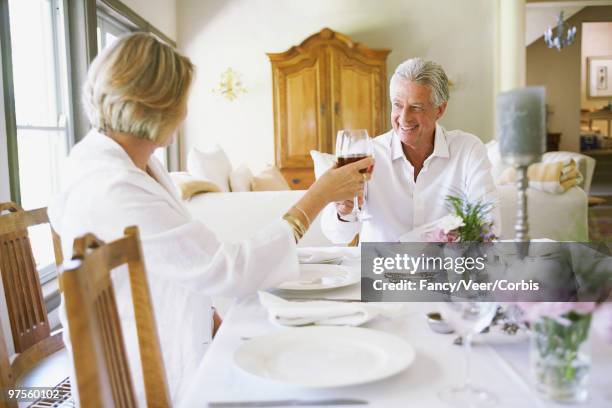 man and woman holding wine glasses - luxury home dining table people lifestyle photography people stock pictures, royalty-free photos & images