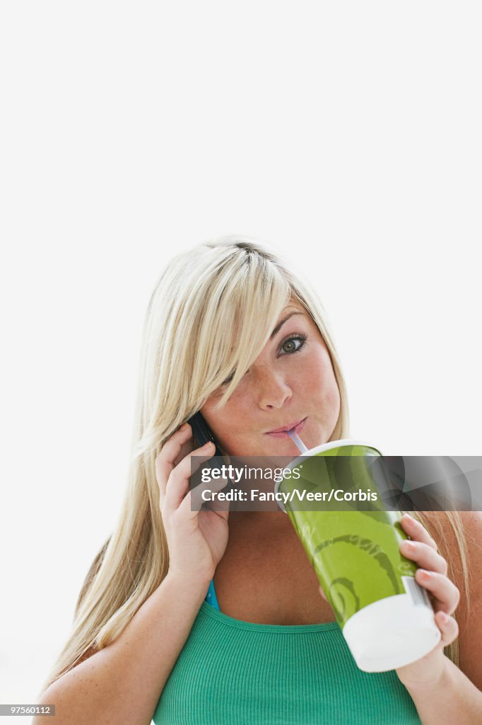 Teenage girl drinking and talking on cell phone