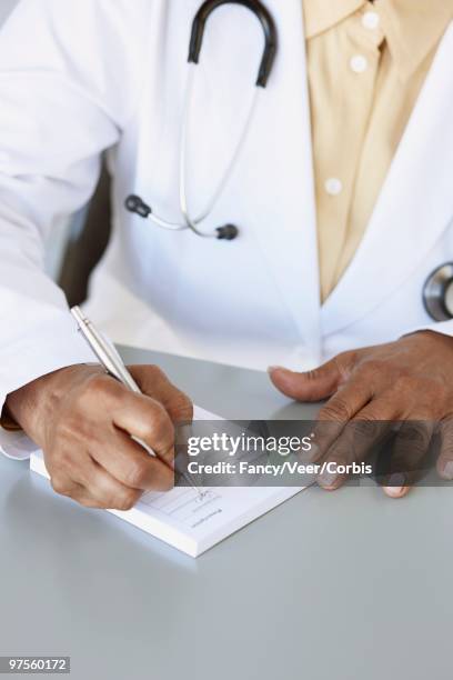doctor writing prescription - 50s woman writing at table stock pictures, royalty-free photos & images